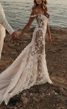 a man and woman holding hands on the beach