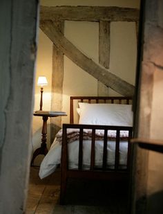 a bed sitting in the middle of a bedroom next to a table with a lamp on it