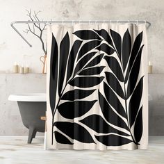 a black and white leaf shower curtain hanging on a bathroom wall next to a bathtub