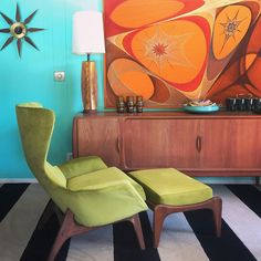 a green chair sitting in front of a painting on the wall next to a dresser