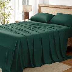 a bed with green sheets and pillows in a room