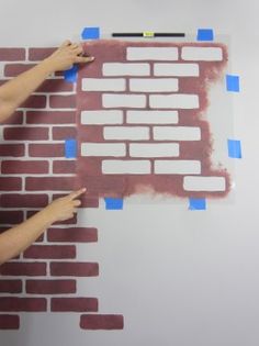 a person painting a brick wall with blue tape