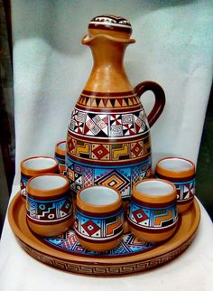 a ceramic pitcher and six cups on a tray