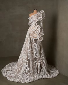 a dress on a mannequin in front of a gray wall with white flowers