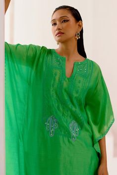 Green kaftan features exquisite dori embroidery and patra work details along its neckline and back. Paired with matching chanderi pant and slip. 
Components: 3
Pattern: Embroiderd
Type Of Work: Patra,Dori Work
Neckline: Notched
Sleeve Type: Flared
Fabric: Silk chanderi
Color: Green
Other Details: 
Model Height: 5ft 9 inches, wearing size S
Occasion: Puja - Aza Fashions Eid Cotton Silk Kurta With Embroidered Neckline, Elegant Festive Palazzo Set With Embroidered Neckline, Designer Embroidered Neckline Kurta Tunic, Festive Cotton Silk Kurta With Embroidered Neckline, Designer Embroidered Neckline Tunic Kurta, Bollywood Style Chanderi Kaftan With Dabka Work, Festive Kurta With Embroidered Neckline In Cotton Silk, Festive Tunic Sets With Embroidered Neckline, Chanderi Straight Kurta Set With Embroidered Neckline