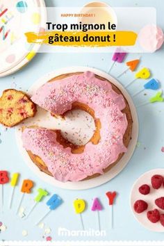 a donut with pink icing and sprinkles is being held by a spoon