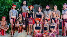 a group of people that are standing in front of some rocks and trees with tattoos on their bodies