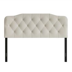 an upholstered headboard with black legs and buttons on the top, against a white background