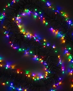 a string of multicolored christmas lights on a black background with the letter o