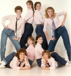 a group of young women posing for a photo together in jeans and pink shirts with their hands on their hipss