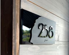 a metal house number sign mounted to the side of a wooden door with numbers on it