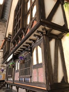 an old building with wooden windows and iron bars on the outside wall, along with flowers in hanging baskets