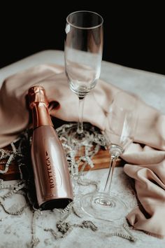 an empty wine glass next to a champagne bottle on a lace covered table cloth with other items