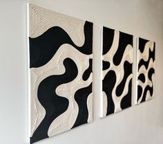 three black and white paintings hanging on the wall