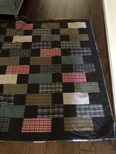 a black and red plaid quilt on the floor next to a wooden floor with a white door