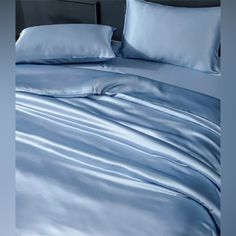 a bed with blue sheets and pillows on it