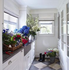 a checkered floor in a white kitchen with flowers on the counter and vases