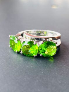 Modern simplicity is executed skilfully in the craftsmanship of this peridot ring. The elegant yet sleek design has such finesse not often seen and an all inspiring neon glow transpires within these green apple like oval cut stones.    This statement piece is the epitome of a green colour in natural peridots and sets a standard three times being perfectly matched to one another in an ever so popular trilogy style mounting. Each stone measures 7.50mm by 5.50mm by 4mm deep with an estimated total weight of 2.40mm and the clarity is clear with a vibrant strong green.  Weight 4.34 grams. Tested 14K. Size M 1/2 (AU/UK) 7.5 (US) and resizable. Layaway--offering flexible plans to suit all. Please follow me on Instagram @lauprells for more photos and videos. Peridot Rings, Neon Glow, Peridot Ring, Green Colour, Green Apple, Gold Flowers, Rings Statement, Oval Cut, Belt Buckles