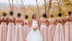 a group of women standing next to each other wearing dresses and holding bouquets in their hands