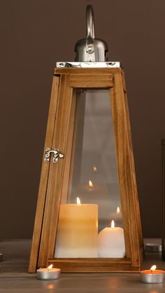 a wooden lantern with two lit candles in it