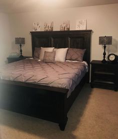 a bedroom with a bed, nightstands and pictures on the wall