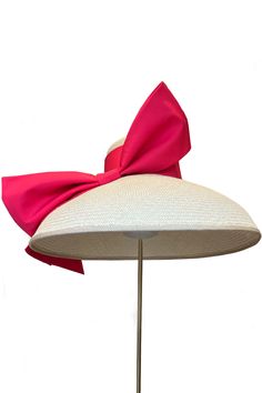 The Audrey Bow Large Brim Hat is a sensational piece of sustainable millinery, designed by Suzannah in collaboration with talented British milliner Ruth Merlin Ravenscroft, and trimmed by hand in her UK atelier. Made from panama straw that has been hand woven in Ecuador. A statement couture hat with deep brim, Audrey is trimmed with a structured bow made of cotton in a vibrant hot pink. Featuring a soft elasticated inner ribbon for a comfortable fit. Pair with our beautiful Garland Dress and oth Elegant Panama Hat With Structured Crown, Curved Brim Sinamay Straw Hat For Royal Ascot, Sinamay Straw Hat With Curved Brim, Elegant Straw Mini Hat With Curved Brim, Pink Garland, Large Brim Hat, Couture Hats, London Boutique, Vintage Couture