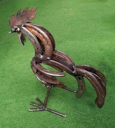 a metal rooster sculpture sitting on top of green grass