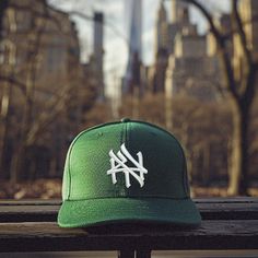 a green hat sitting on top of a wooden bench in front of a cityscape