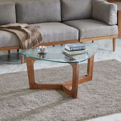 a glass coffee table sitting on top of a carpeted floor next to a couch