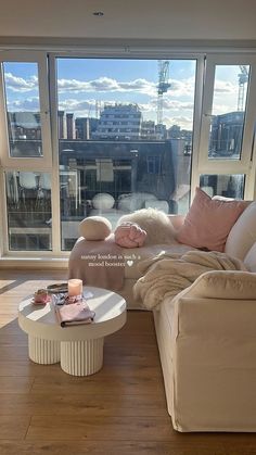 a living room filled with furniture and a large window overlooking the cityscape in the distance