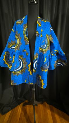 An elegant blue mustard with black, gray, and white mid-length kimono accents is the perfect African print for any event. You can style this kimono with a dress, skirt, or dress pants or dress down with denim or leggings. Why not add this kimono to your wardrobe? Blue Stretch Cotton Outerwear, Spring Workwear Kimono With Kimono Sleeves, Spring Workwear Kimono, Blue Printed Outerwear For Spring, Casual Indigo Kimono For Spring, Fitted Casual Kimono With Kimono Sleeves, Fitted Blue Kimono For Summer, Casual Fitted Kimono With Kimono Sleeves, Fitted Blue Summer Kimono