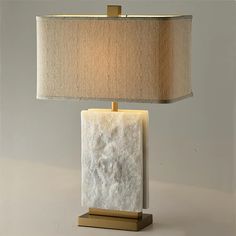 a table lamp with a white marble block on it and a beige shade over the base