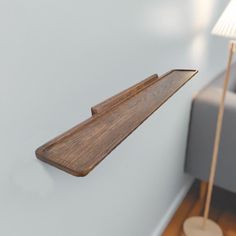 a wooden shelf mounted to the side of a white wall next to a gray couch