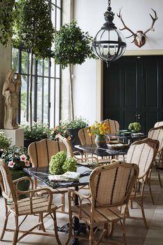 an outdoor dining area with wicker chairs and black table surrounded by potted plants