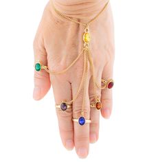 a woman's hand with five different colored stones on it and a gold chain