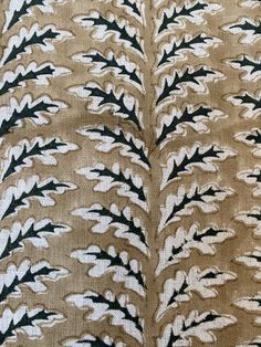 the back side of a brown and white fabric with black leaves on it's sides