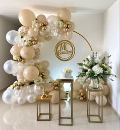 balloons and flowers decorate the entrance to an event with gold, white and silver accents