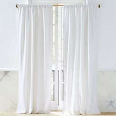 a white curtain hanging from the side of a window in front of a marble wall