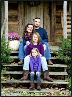 a family sitting on steps in front of a wooden building