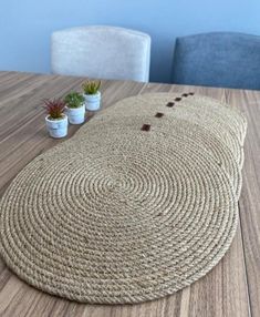 a round rug sitting on top of a wooden table next to two potted plants