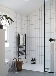 a white tiled bathroom with a black and white towel rack