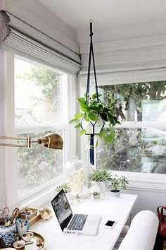 a laptop computer sitting on top of a white desk in front of a large window