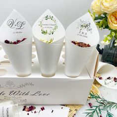 four white cups with floral designs on them are sitting in a box next to flowers