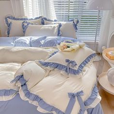 a bed with blue and white ruffles on the comforter, pillows and pillow cases