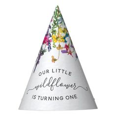 a white party hat with colorful flowers and the words our little wildflowers is turning one