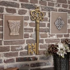 there is a gold key on the wall next to some pictures and flowers in vases