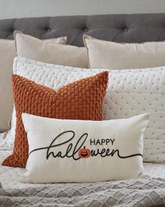 a bed with two pillows and a pillow that says happy halloween written on the front