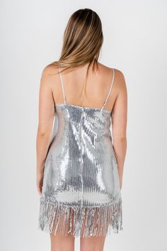 a woman wearing a silver sequin dress with fringes on the bottom and back