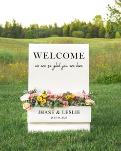 a welcome sign in the grass with flowers