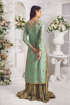 Stunning Sage-green long shirt crafted from Pure silk net, embellished with tila, dabka, nakshi, sequins, pearls, crystals & resham work, pop of red hue and shimmer appliques on hem lines and hand-made tassels to enhance the look of this shirt. Heavily embellished dupatta in breath taking Mukesh work with gold & silver in stunning geometric pattern makes this an absolute favorite, crushed jamawar lehenga completes the look of this outfit. Shirt Fabric: Pure Silk Net Shirt Length: 48” (customisab Green Embellished Semi-stitched Anarkali Set, Bollywood Style Embellished Green Anarkali Set, Embellished Green Georgette Anarkali Set, Traditional Embellished Green Palazzo Set, Embellished Pista Green Anarkali Set For Eid, Green Embellished Floor-length Kurta, Eid Embellished Pista Green Lehenga, Eid Embellished Pista Green Kurta, Festive Embellished Green Sharara